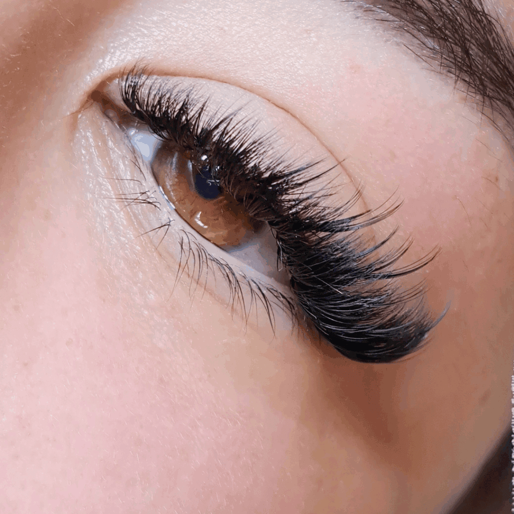 Close-up of a woman's eye with professionally applied eyelash extensions, showcasing beauty and precision.